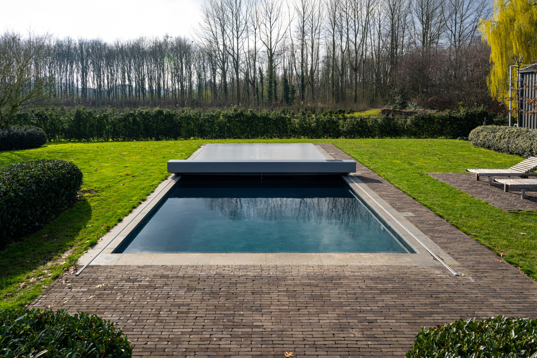 Vue sur une piscine équipée d une Coverseal au milieu de la verdure.